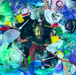 Image showing Man drowning in ocean water under plastic recipients pile, environment concept