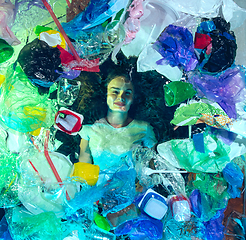 Image showing Woman drowning in ocean water under plastic recipients pile, environment concept