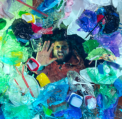 Image showing Man drowning in ocean water under plastic recipients pile, environment concept