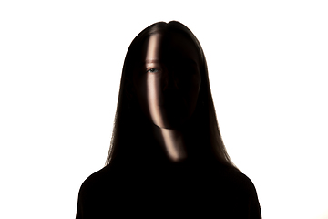 Image showing Dramatic portrait of a girl in the dark on white studio background.