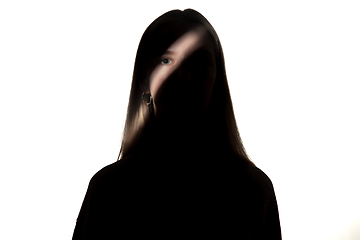 Image showing Dramatic portrait of a girl in the dark on white studio background.