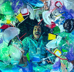 Image showing Man drowning in ocean water under plastic recipients pile, environment concept