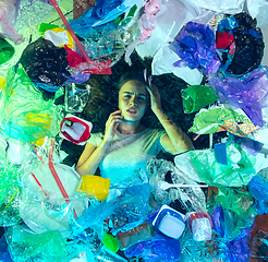 Image showing Woman drowning in ocean water under plastic recipients pile, environment concept