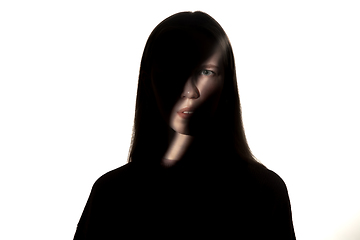 Image showing Dramatic portrait of a girl in the dark on white studio background.