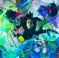 Image showing Woman drowning in ocean water under plastic recipients pile, environment concept