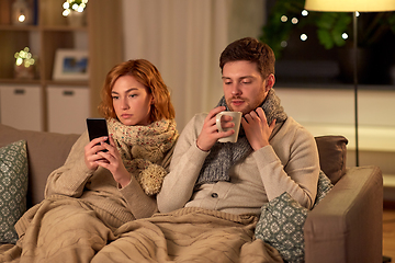 Image showing sick young couple with smartphone at home