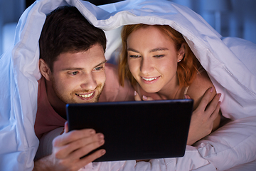 Image showing happy couple using tablet pc in bed at night