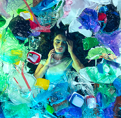 Image showing Woman drowning in ocean water under plastic recipients pile, environment concept