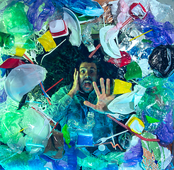 Image showing Man drowning in ocean water under plastic recipients pile, environment concept