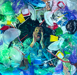 Image showing Man drowning in ocean water under plastic recipients pile, environment concept