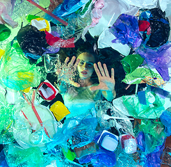 Image showing Woman drowning in ocean water under plastic recipients pile, environment concept