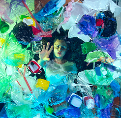 Image showing Woman drowning in ocean water under plastic recipients pile, environment concept