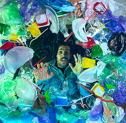 Image showing Man drowning in ocean water under plastic recipients pile, environment concept