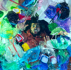 Image showing Man drowning in ocean water under plastic recipients pile, environment concept