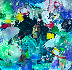 Image showing Man drowning in ocean water under plastic recipients pile, environment concept