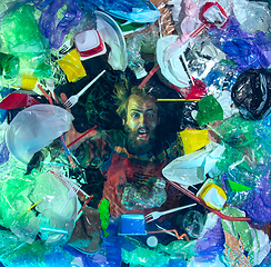 Image showing Man drowning in ocean water under plastic recipients pile, environment concept