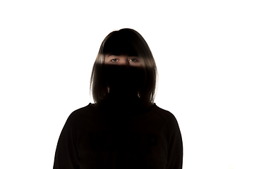 Image showing Dramatic portrait of a girl in the dark on white studio background.