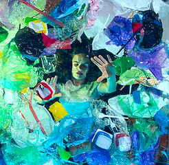 Image showing Woman drowning in ocean water under plastic recipients pile, environment concept