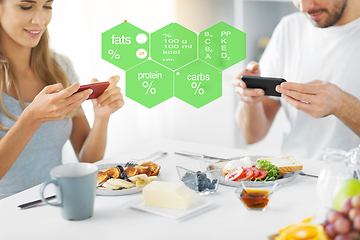 Image showing couple with smartphones having breakfast at home