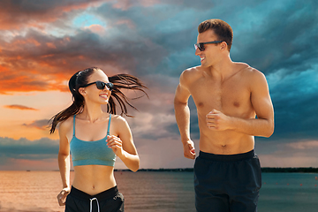 Image showing couple in sports clothes running along over sea