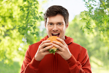 Image showing happy young man eating hamburger