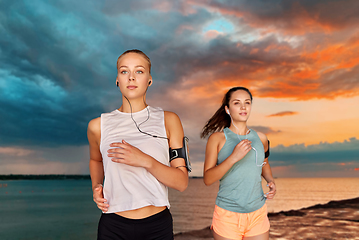 Image showing young women with earphones and smartphones running