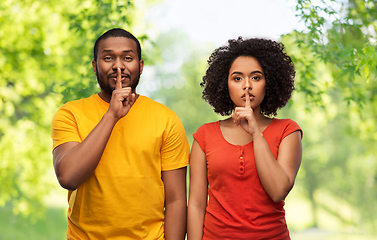 Image showing happy african american couple making hush gesture