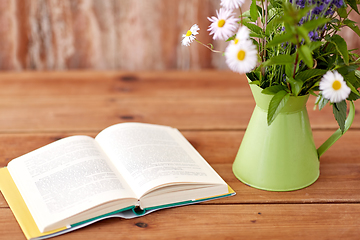 Image showing book and flowers in jug on wooden table