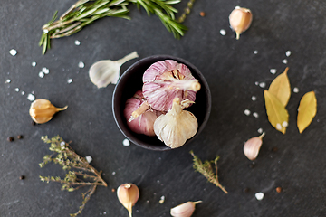 Image showing garlic in bowl and rosemary on stone surface