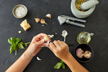 Image showing hands peeling garlic with knife for pesto sauce