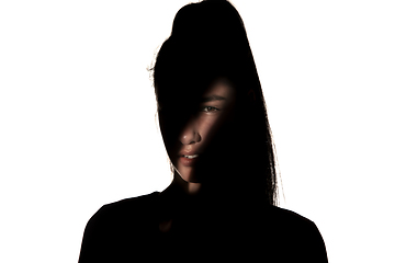 Image showing Dramatic portrait of a girl in the dark on white studio background.