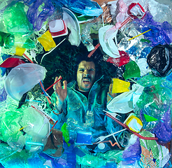 Image showing Man drowning in ocean water under plastic recipients pile, environment concept