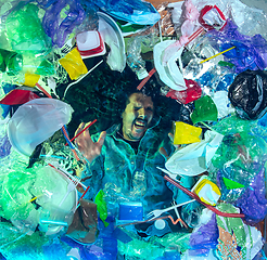 Image showing Man drowning in ocean water under plastic recipients pile, environment concept