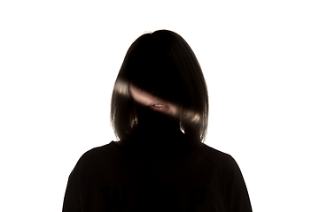 Image showing Dramatic portrait of a girl in the dark on white studio background.