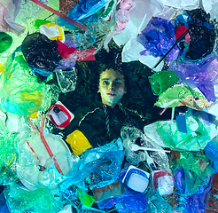 Image showing Woman drowning in ocean water under plastic recipients pile, environment concept