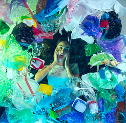 Image showing Woman drowning in ocean water under plastic recipients pile, environment concept