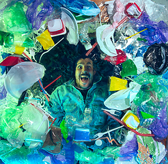 Image showing Man drowning in ocean water under plastic recipients pile, environment concept