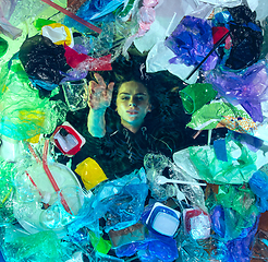 Image showing Woman drowning in ocean water under plastic recipients pile, environment concept