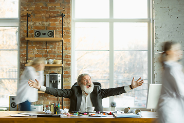 Image showing Tired boss resting at his workplace while people moving near blurred