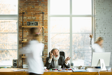 Image showing Tired boss resting at his workplace while people moving near blurred