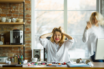 Image showing Nervous and tired boss at her workplace busy while people moving near blurred