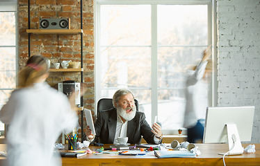 Image showing Tired boss resting at his workplace while people moving near blurred