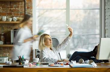 Image showing Tired boss resting at her workplace while people moving near blurred