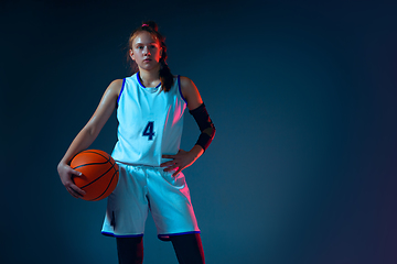 Image showing Young caucasian female basketball player on blue studio background in neon light