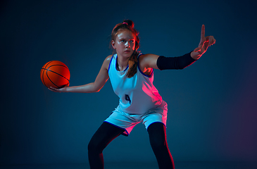 Image showing Young caucasian female basketball player on blue studio background in neon light