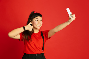 Image showing Asian teenager\'s portrait isolated on red studio background