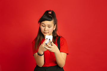 Image showing Asian teenager\'s portrait isolated on red studio background