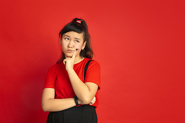 Image showing Asian teenager\'s portrait isolated on red studio background