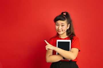 Image showing Asian teenager\'s portrait isolated on red studio background