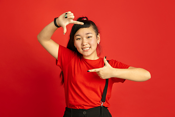 Image showing Asian teenager\'s portrait isolated on red studio background